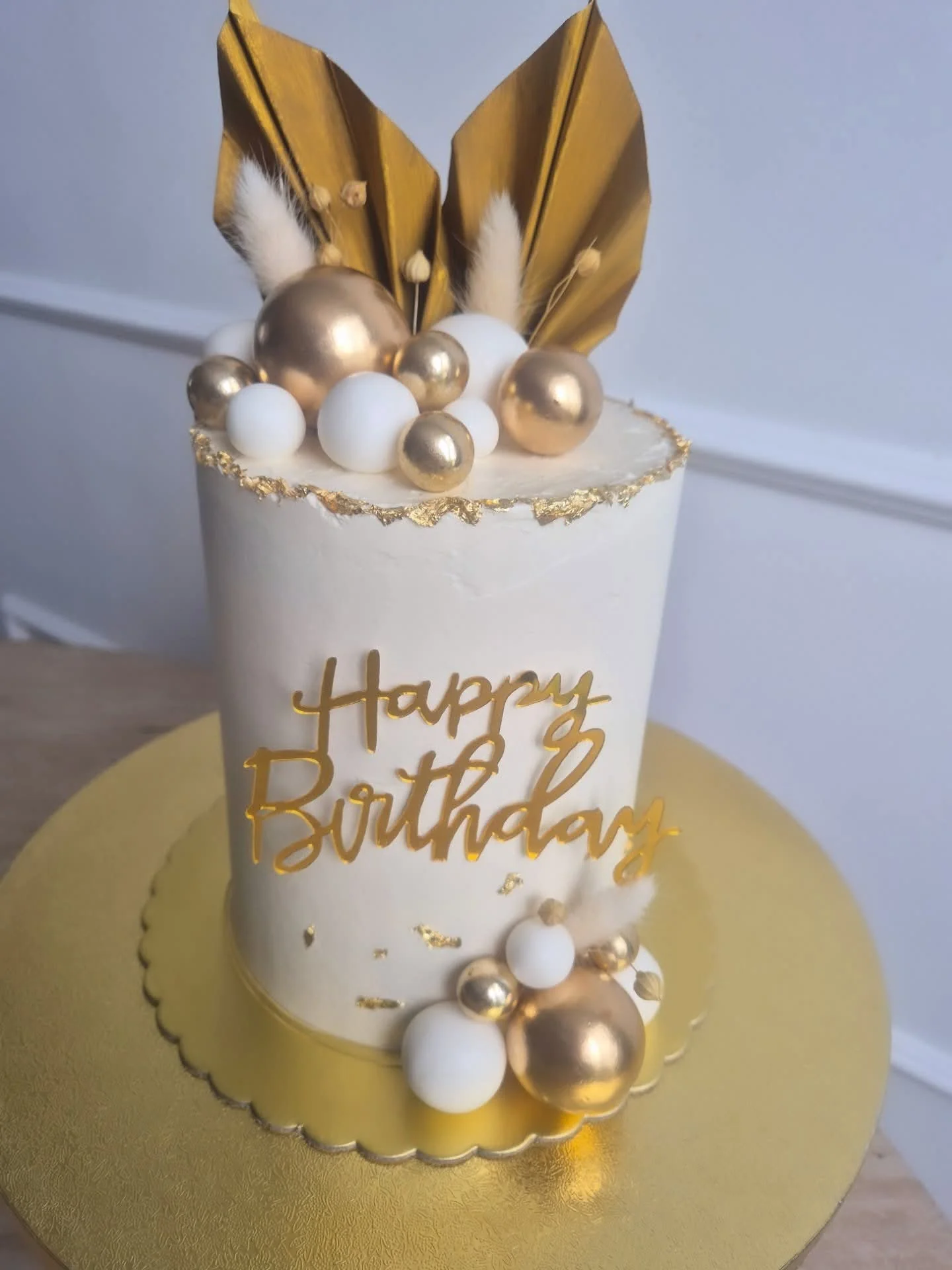Gâteau d'anniversaire blanc et or avec feuilles dorées - création Emra Gâteaux